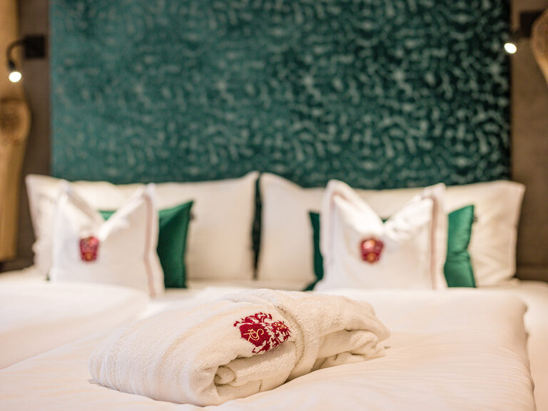 Ein Bademantel mit dem Signet des Landhaus Sponsel-Regus liegt auf einem Bett.