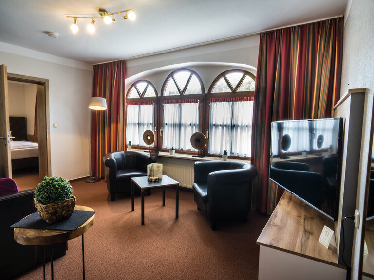 Ein modernes Wohnzimmer im Landhaus Hotel Sponsel-Regus bietet gemütliche Sitzgelegenheiten sowie einen TV.