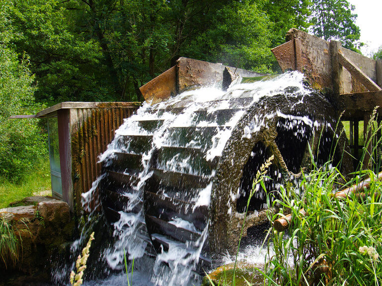 Wasser fliesst über ein Wasserrad.